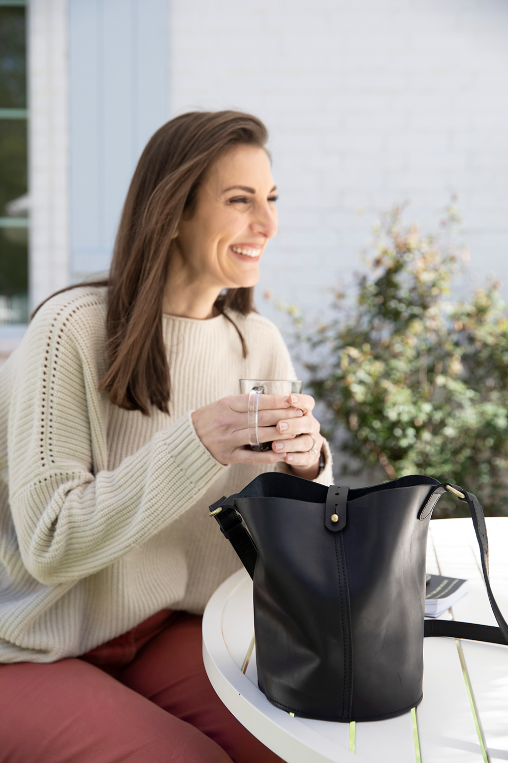 Woman sitting outdoors with a black handbag and glass of water