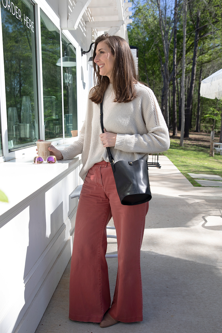 Woman standing outside a building with a black handbag