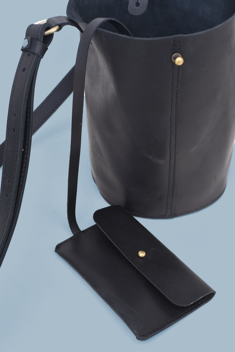 Black leather handbag with matching pouch on a light blue background