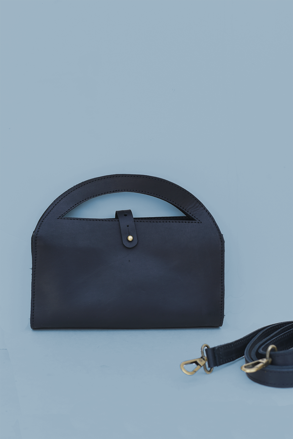 Black handbag with a strap on a light blue background