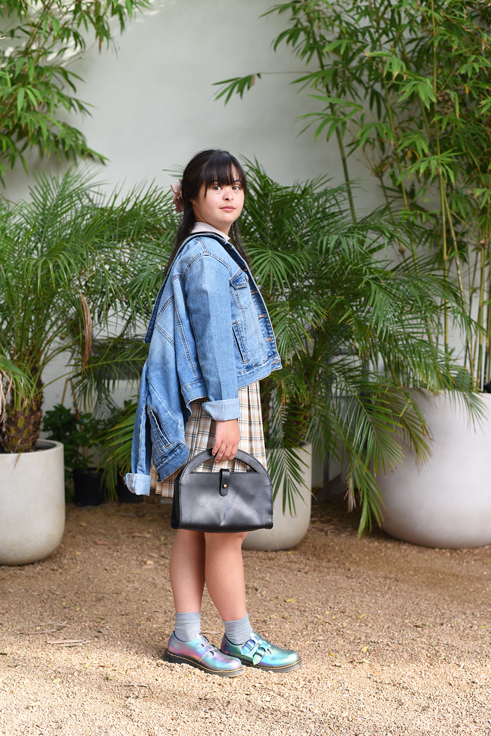 Woman in a denim jacket standing among potted plants