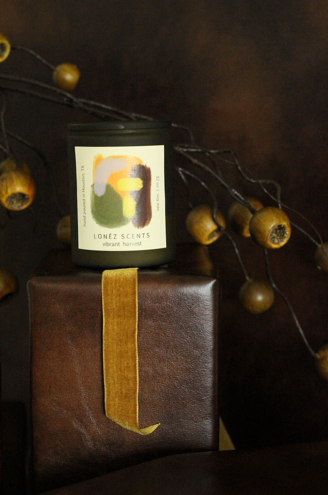 Candle with a label on a brown gift box against a dark background