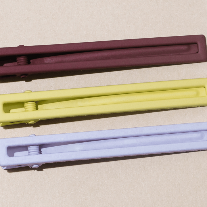 aset of 3 hairlips, one brown, one yellow, one white, on a tan background