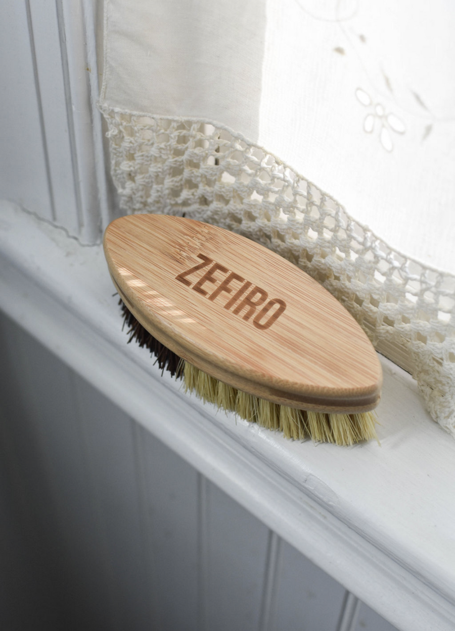 Wooden brush with bristles on a white surface, branded 'Zefiro'.