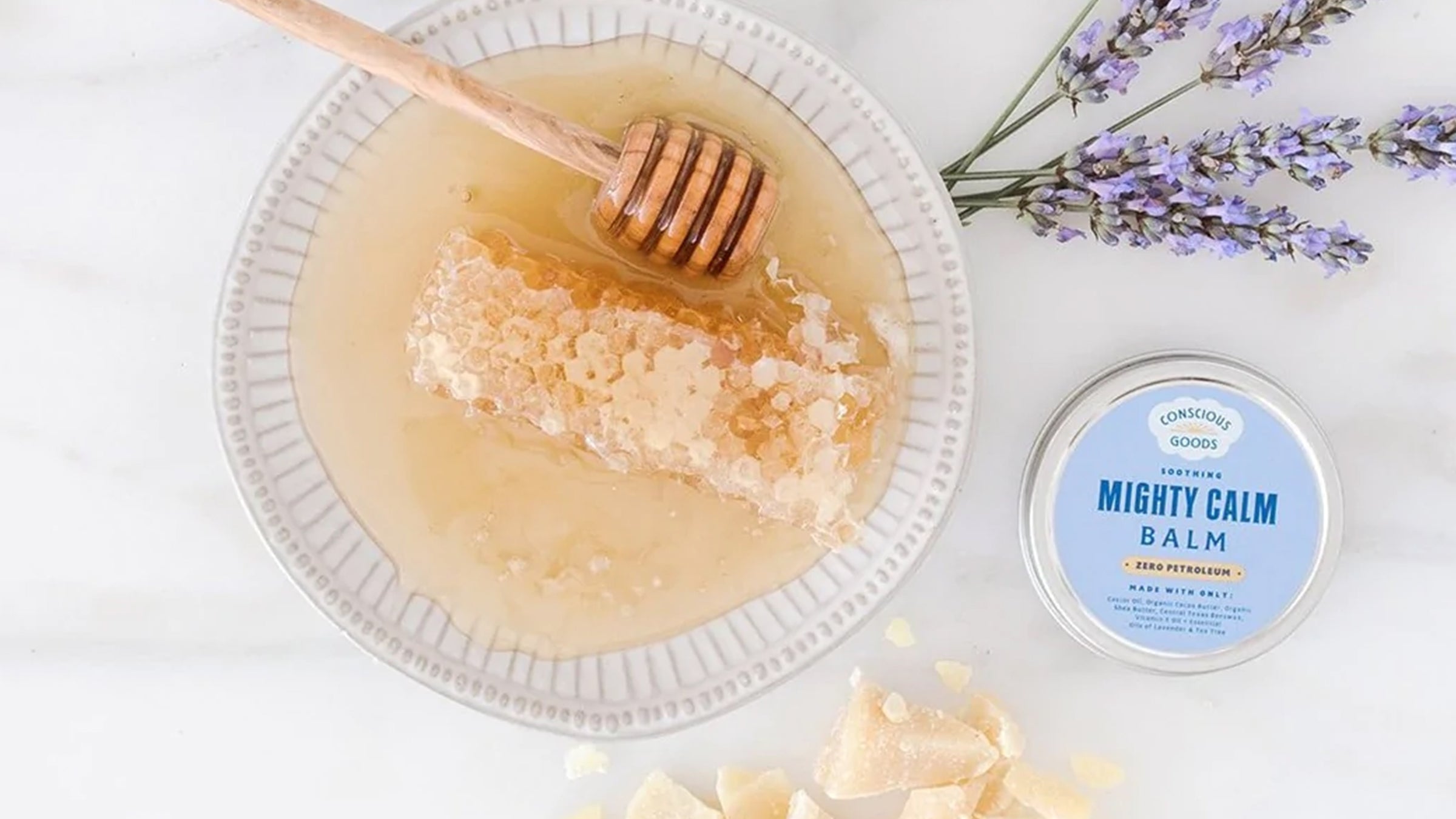 Conscious Goods Mighty Calm balm on marble countertop next to honey and lavendar
