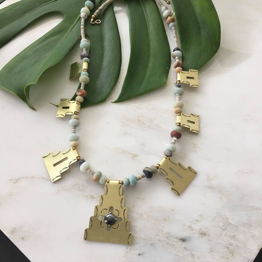  HARVEST Necklace >> Seven textured &amp; hand stamped brass shapes with prong set semi-precious stone on the center piece. This statement necklace is finished with multi colored amazonite beads and a 14k gold filled clasp. Necklace is 23” long. Center gemstone options are black onyx or hematite. 