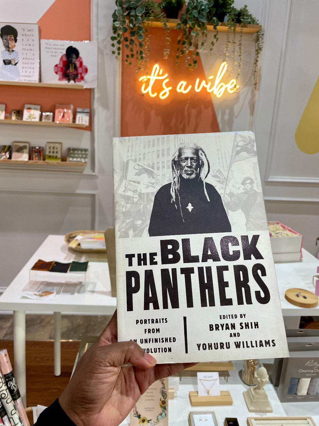 A person holding a book titled 'The Black Panthers' in a bookstore environment.