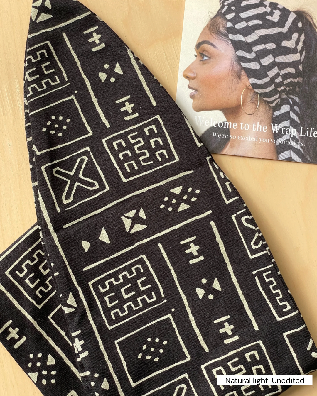 Black fabric with white geometric patterns held by a person wearing a matching headscarf.