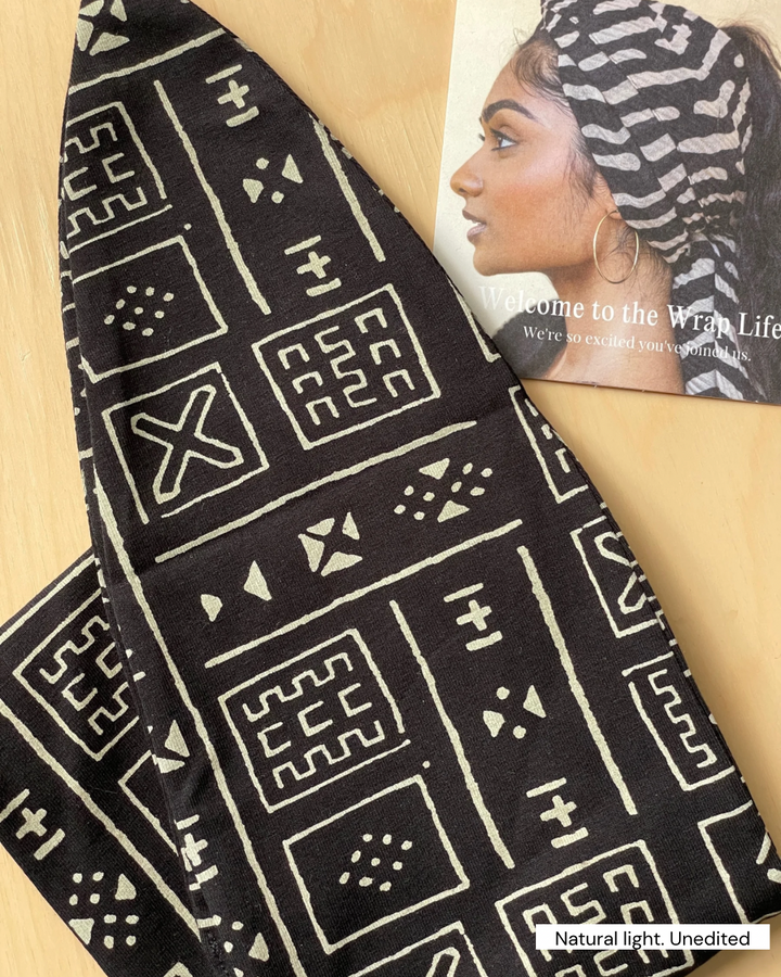 Black fabric with white geometric patterns held by a person wearing a matching headscarf.