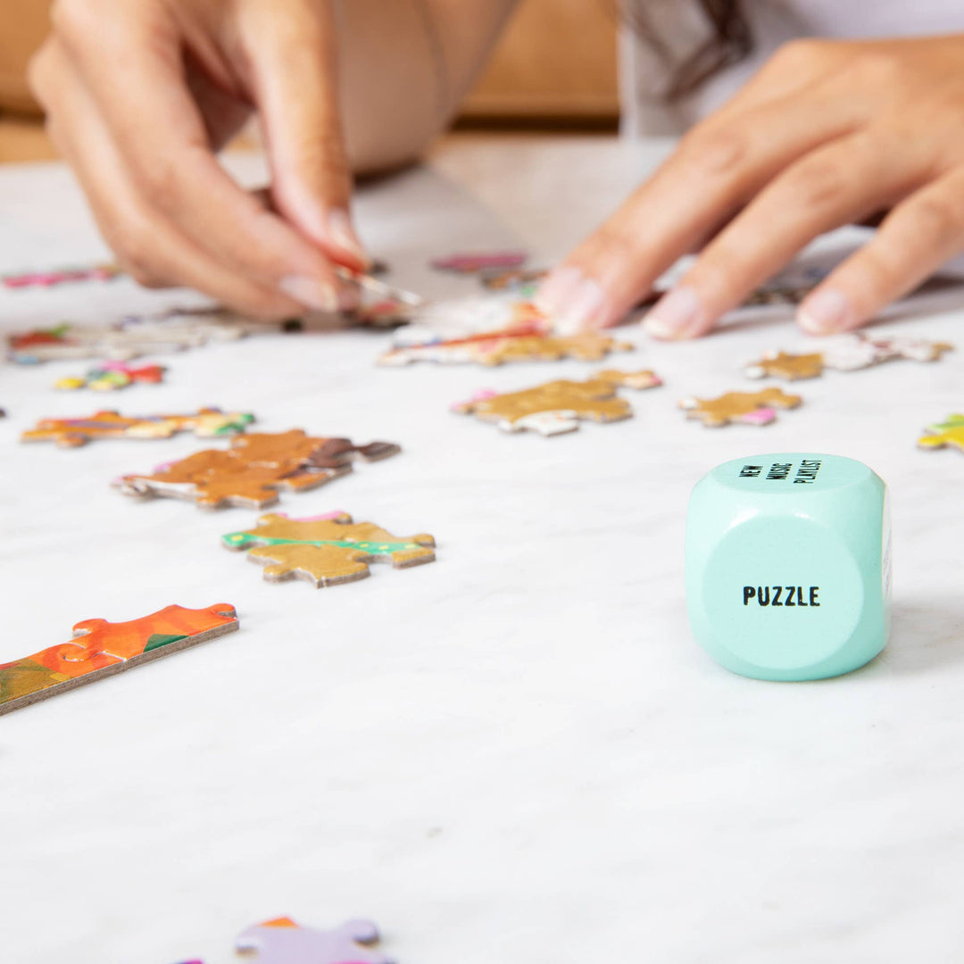 Person working on a puzzle with a completed puzzle piece and a container labeled 'Puzzle' in the foreground.
