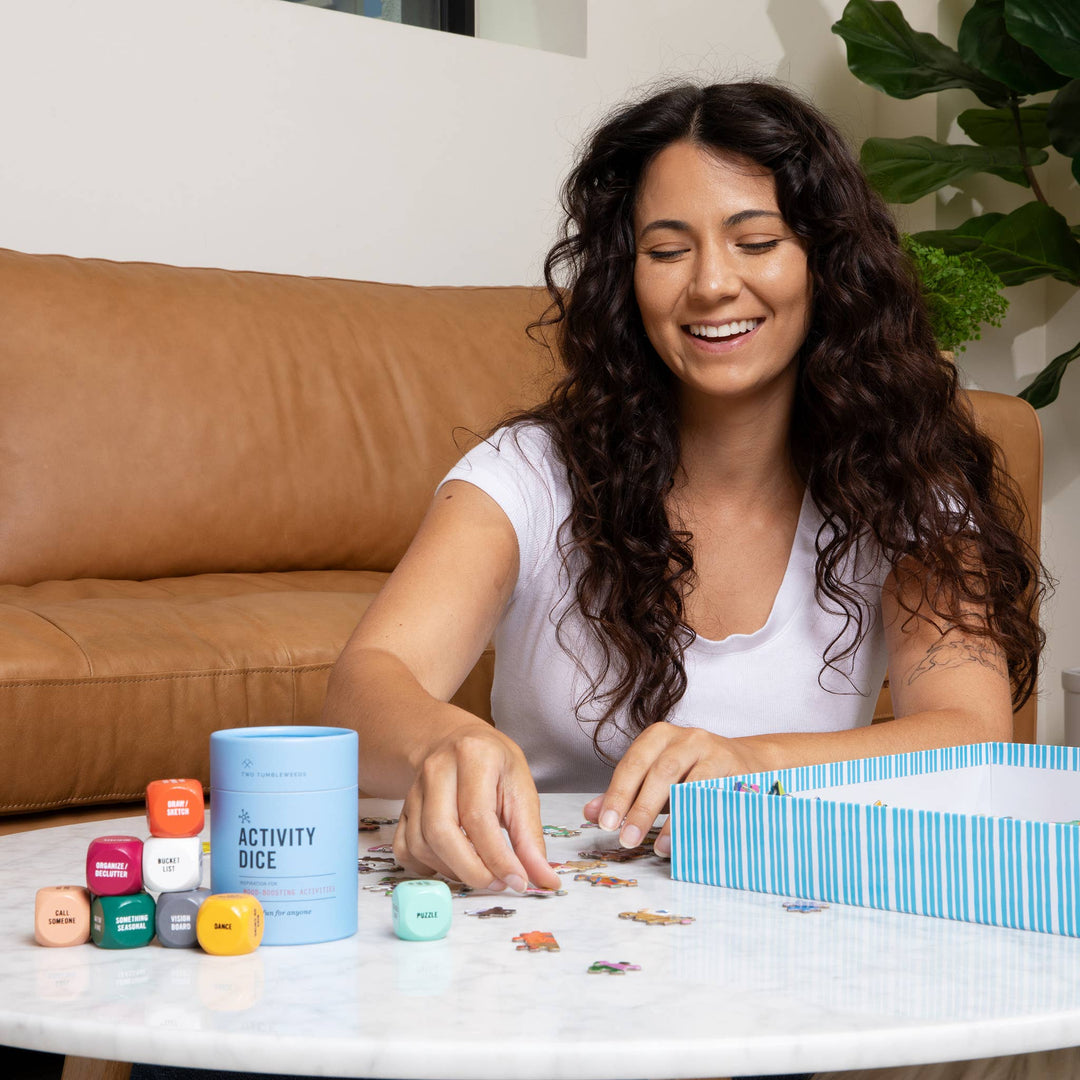Woman playing with a puzzle and dice on a table, with a couch and plant in the background.