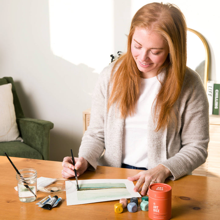 Woman painting at a table with art supplies