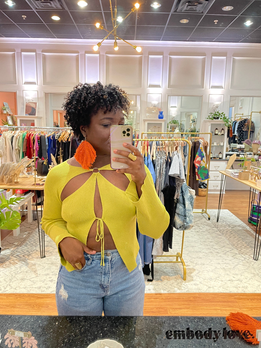 woman taking a selfie wearing orange macrame earrings