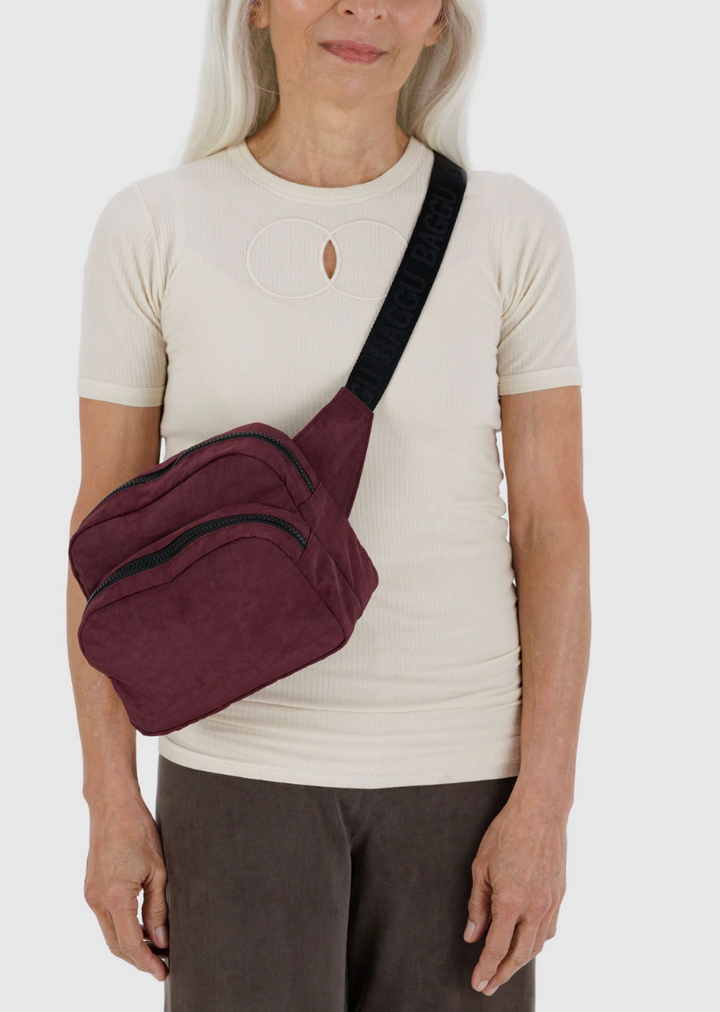 person in creame top and brown bottoms wearing baggu fanny pack in mahogany across chest