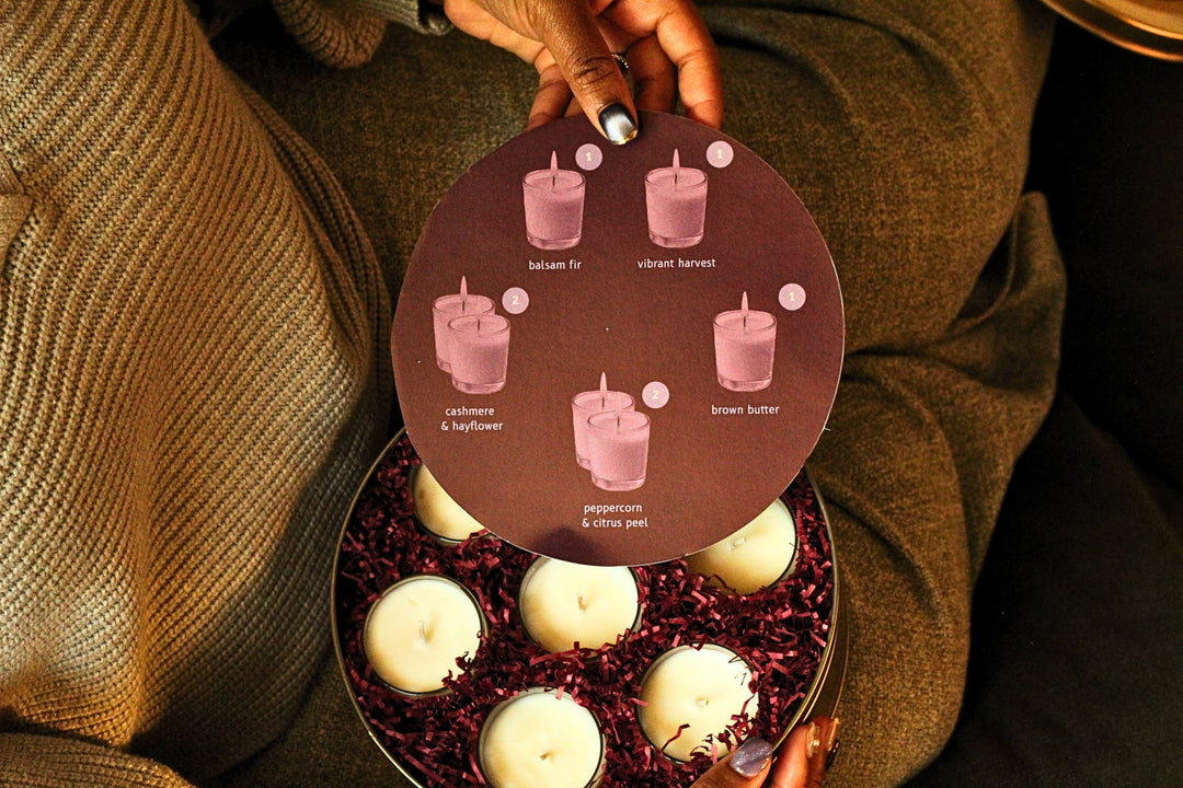 Person holding a round box with candles and a flavor card.
