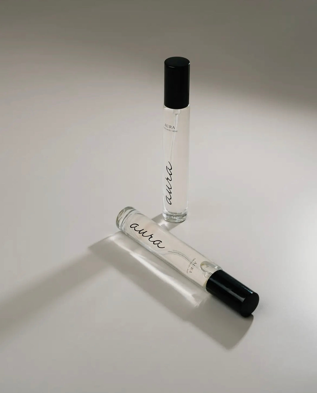 Two small glass bottles with black caps labeled 'aura' on a light gray background.