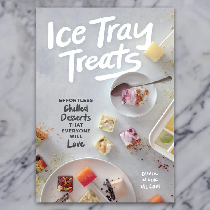A book named Ice Tray Treats on a marble background. The book has various ice cube desserts on the cover.