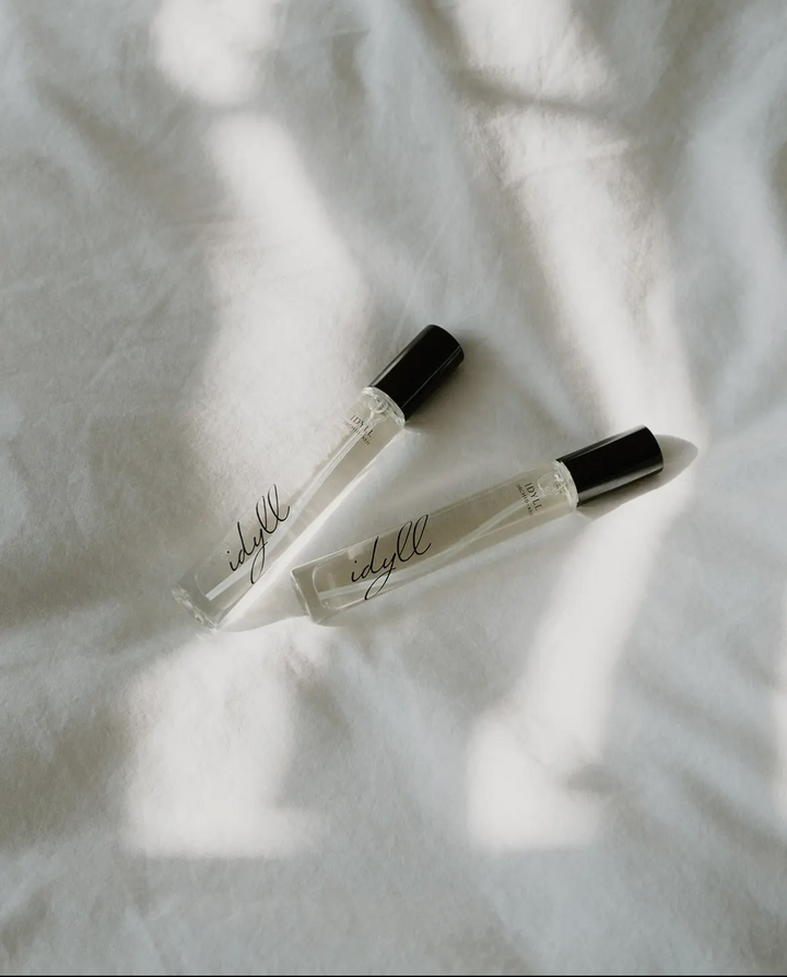 Two small perfume bottles with 'edifyl' branding on a light fabric background