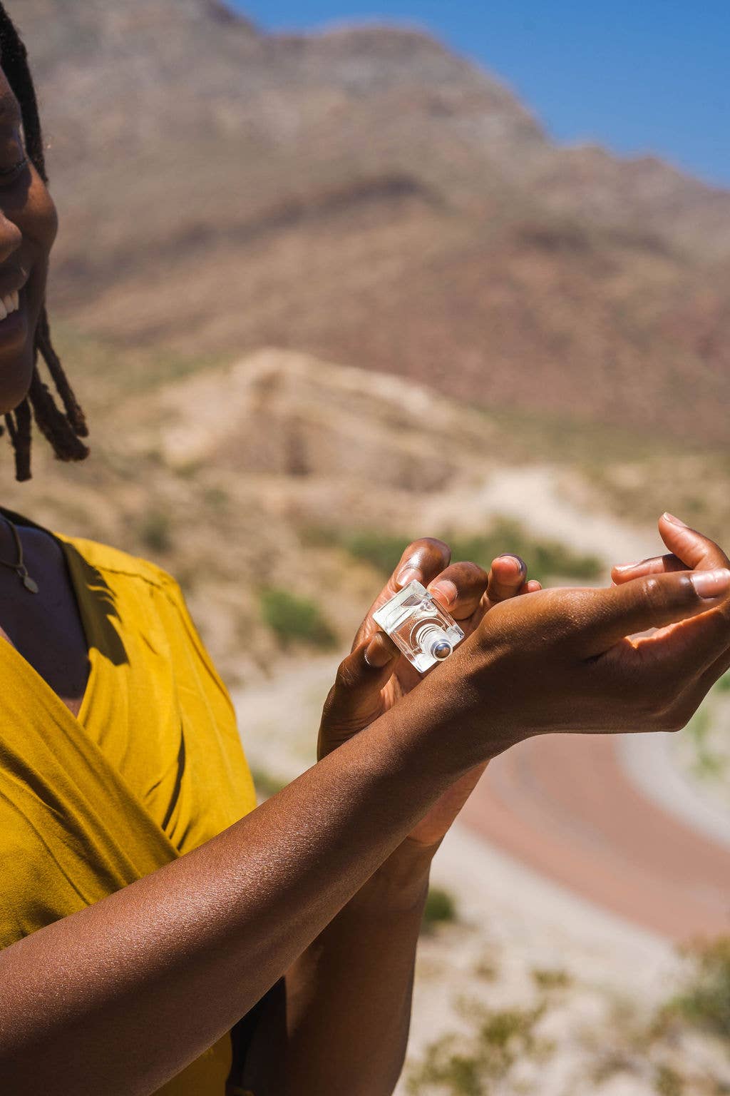 Person applying fragrance oil on a mountainous landscape