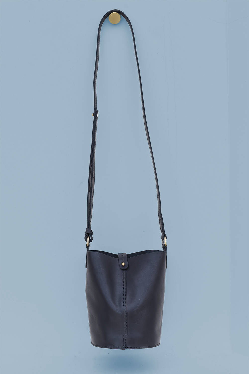 Black leather crossbody bag on a light blue background