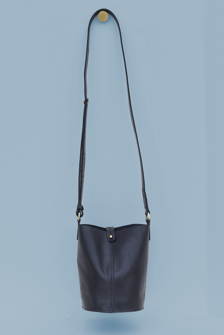 Black leather crossbody bag on a light blue background