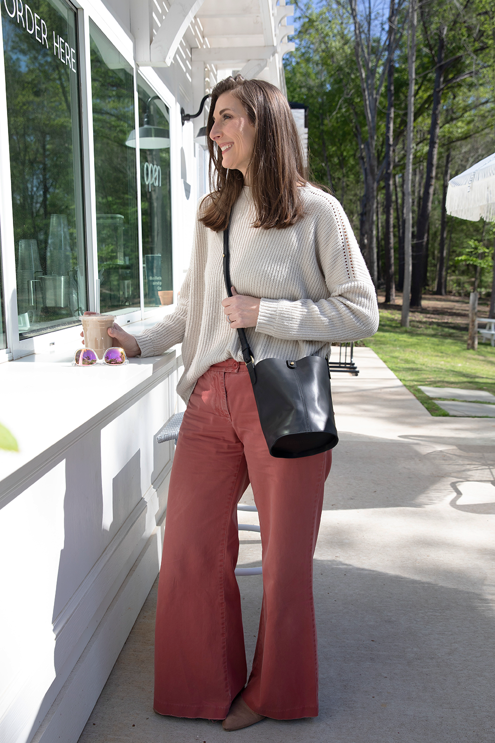 Woman standing outside a building with a black handbag