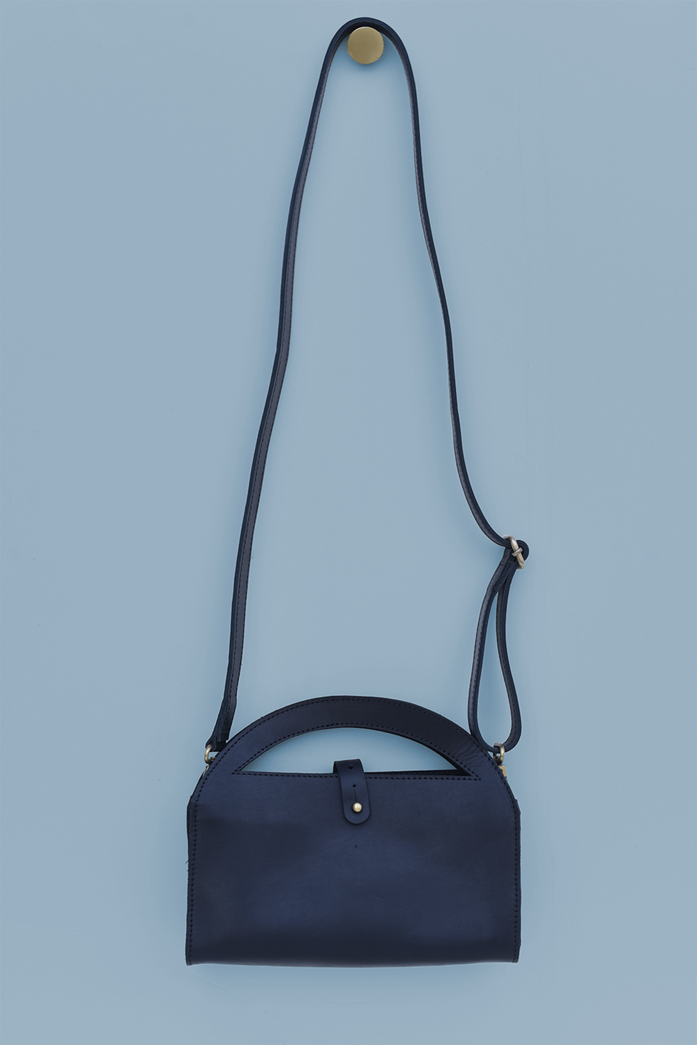 black handbag with a strap on a light blue background