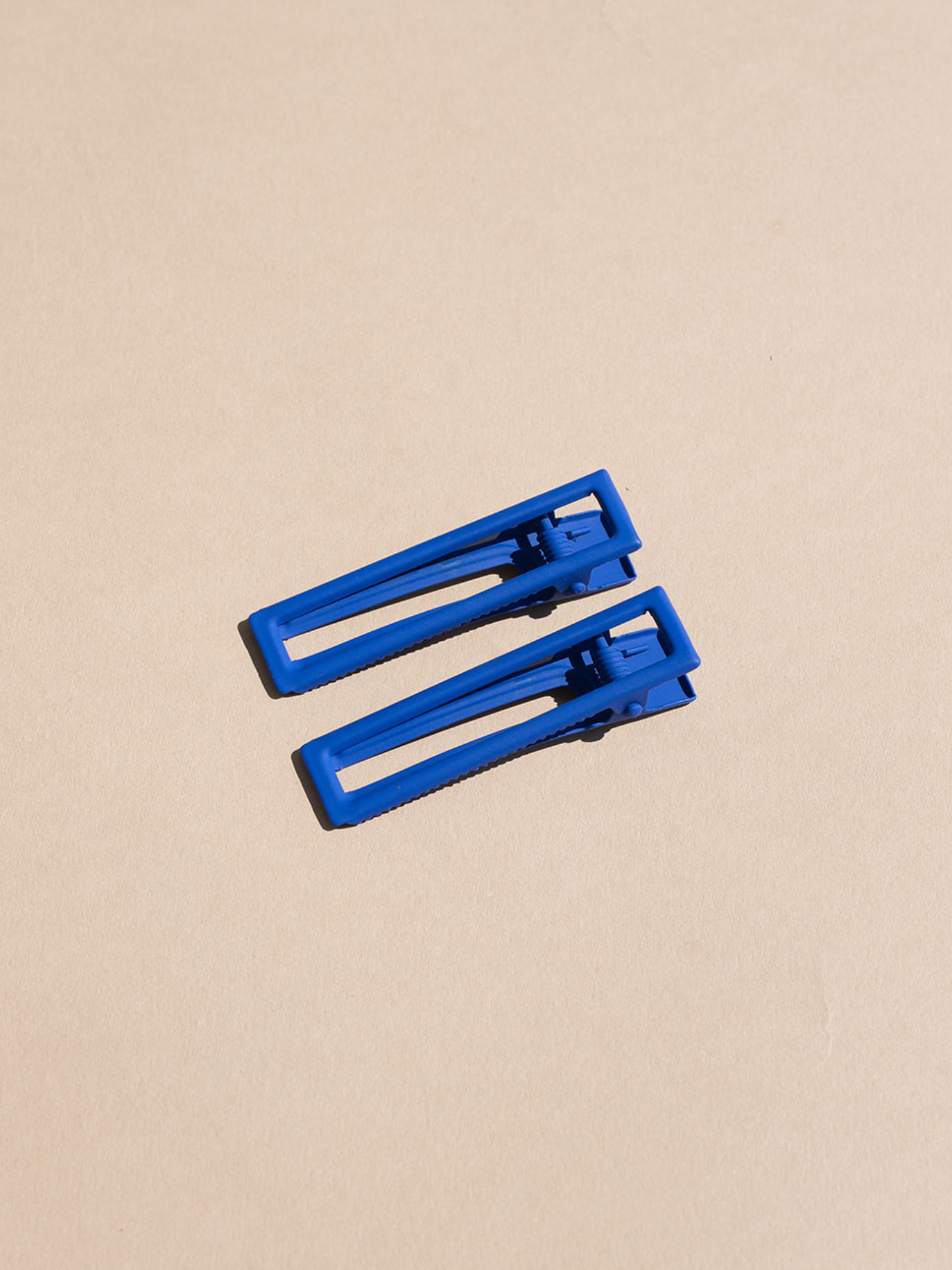 two blue hair clips on tan background