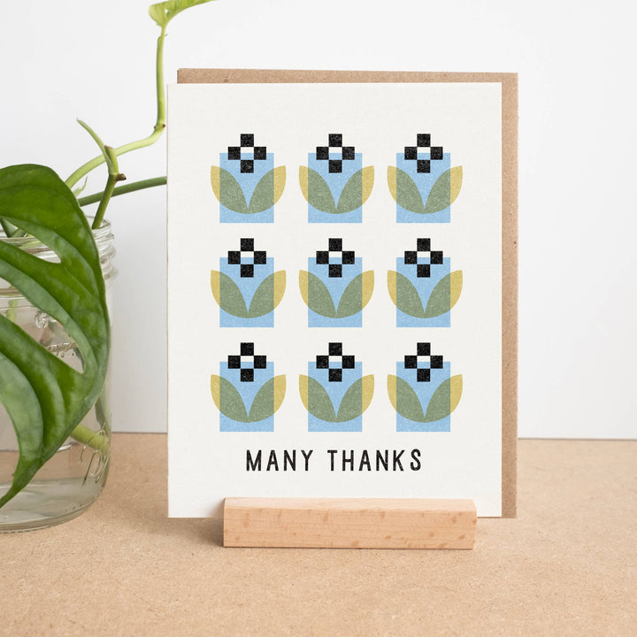 Greeting card with geometric design and 'Many Thanks' text on a wooden stand.
