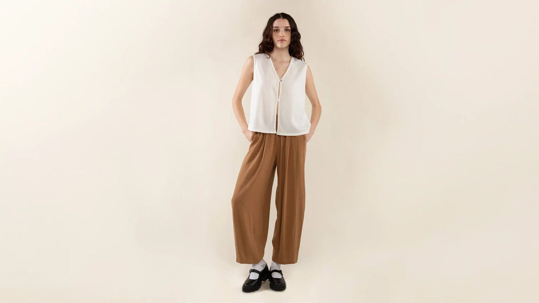 A female model wearing a white NLT vest and brown BLT pants