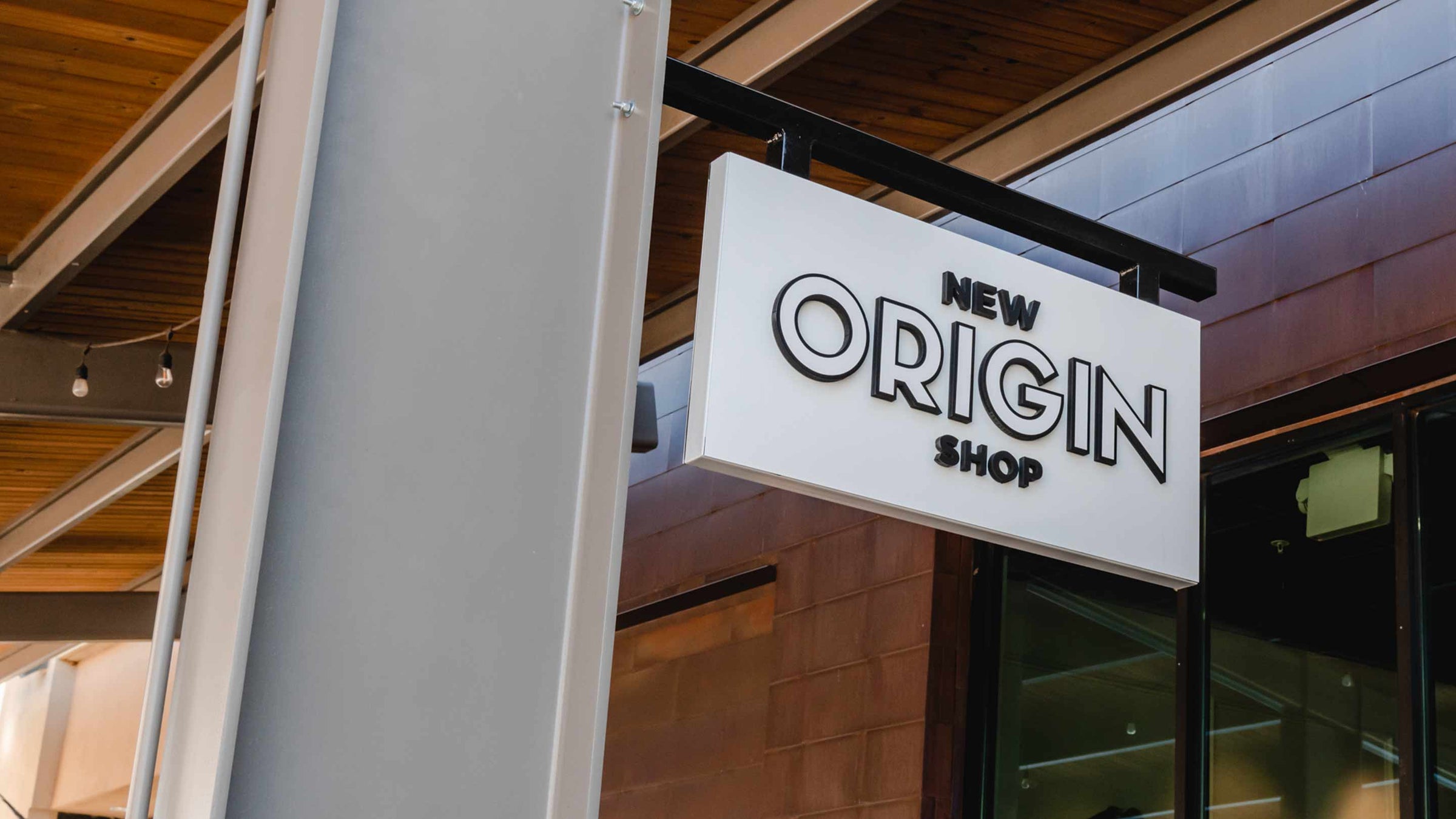 New Origin Shop's Front hanging sign in white