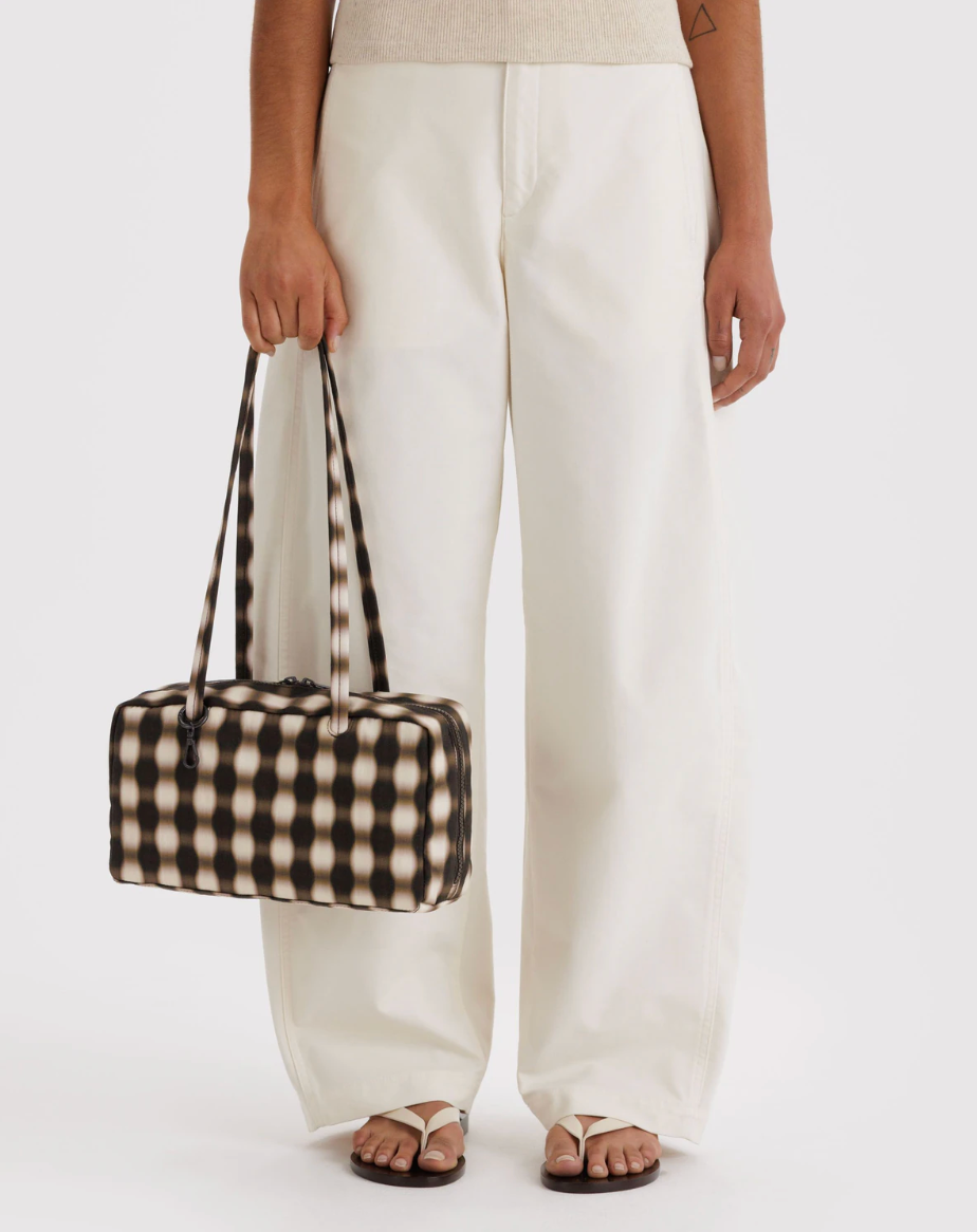 person in light top and bottoms against white backdrop holding Nylon Bowler Bag: Blurred Gingham Brown