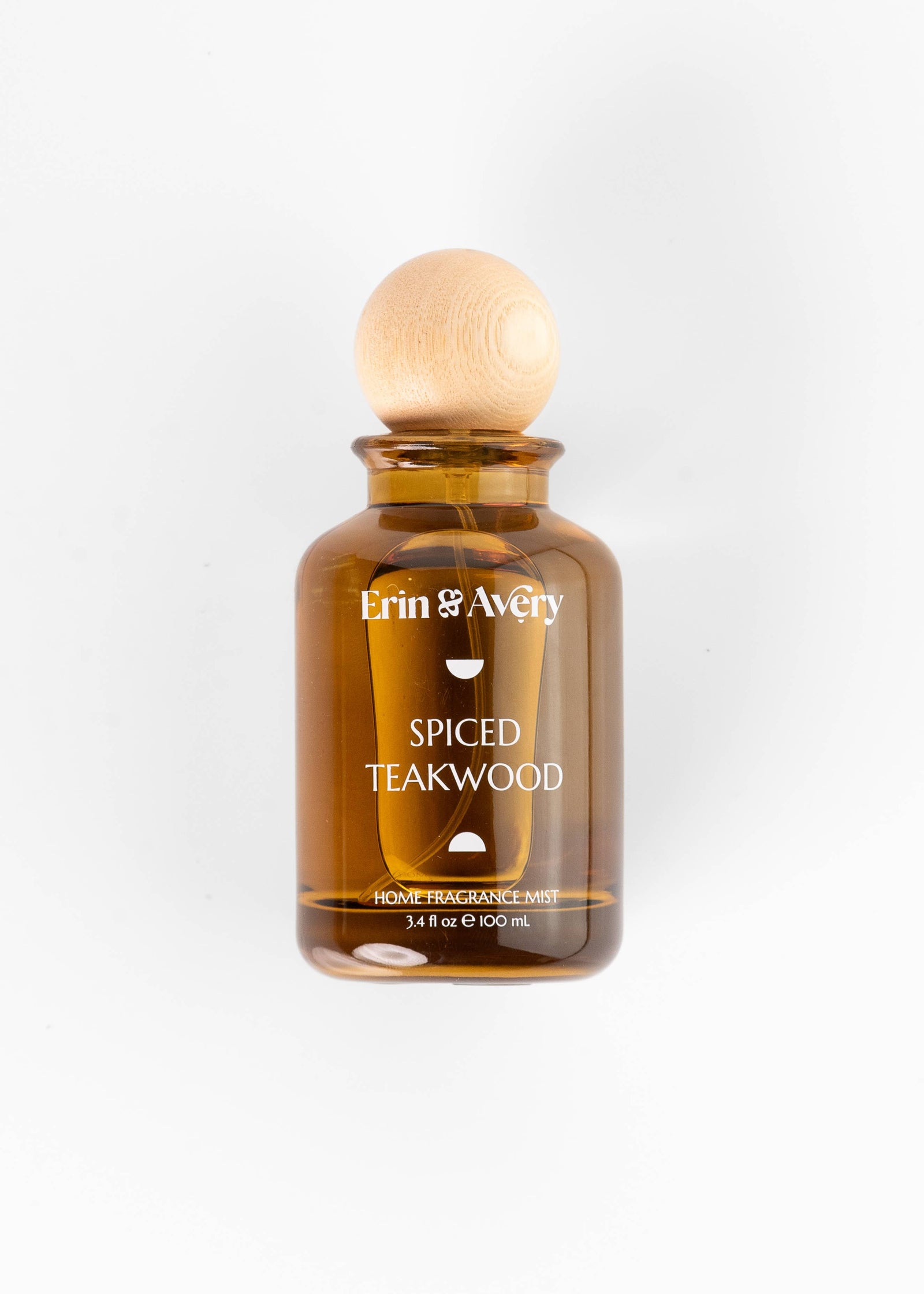 A bottle of Erin & Avery Spiced Teakwood home fragrance mist in an amber glass bottle with a light wood spherical cap, centered on a white background.