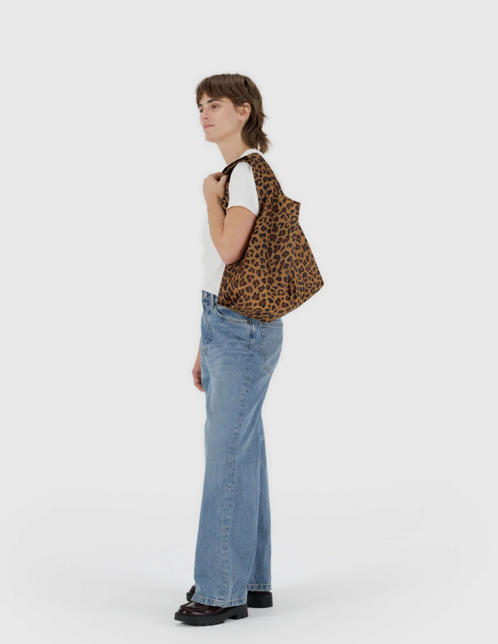 Person wearing a leopard print bag and blue jeans on a white background