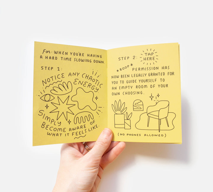 Hand holding a yellow booklet with illustrated text and graphics on a white background