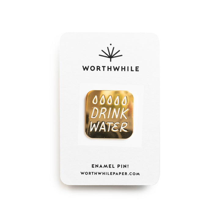 Enamel pin with 'Drink Water' text on a white card with 'Worthwhile' branding.