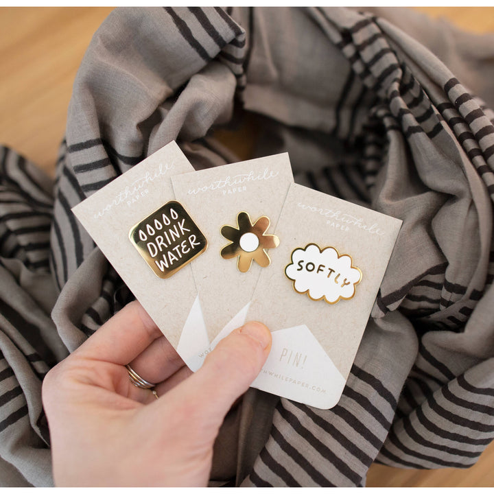 Hand holding a card with decorative pins against a striped fabric background