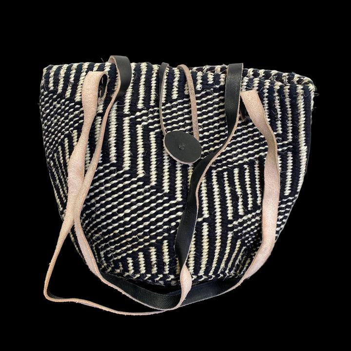 Black and white patterned bag with beige straps on a wooden surface