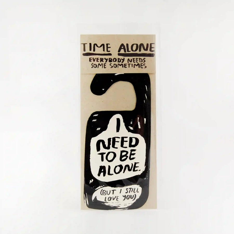 a black door hanger in packaging. The hanger reads "I need to be alone but I still love you"