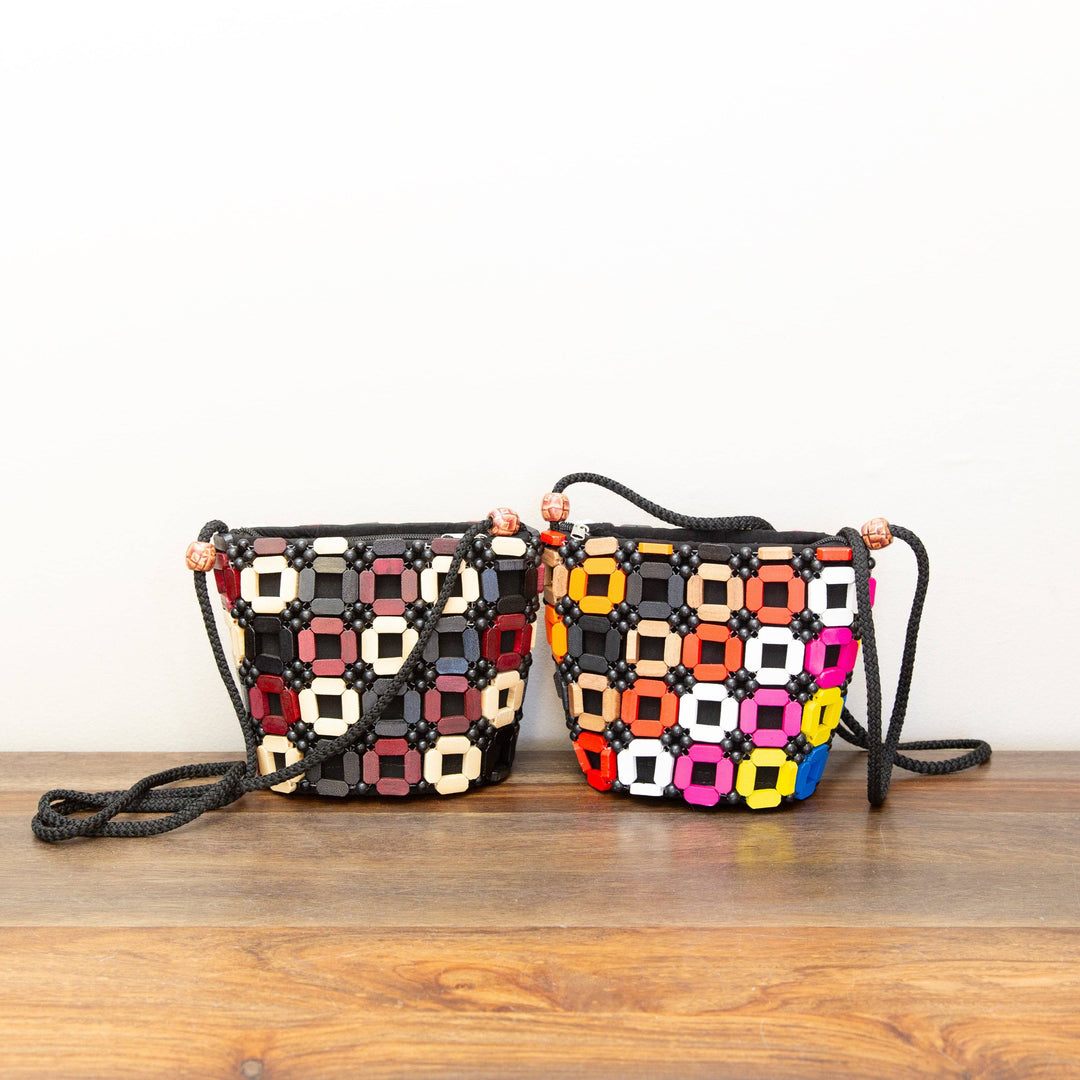 Two colorful handbags with geometric patterns on a wooden surface.