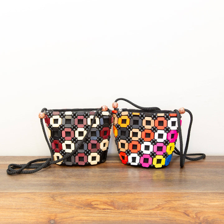 Two colorful handbags with geometric patterns on a wooden surface.