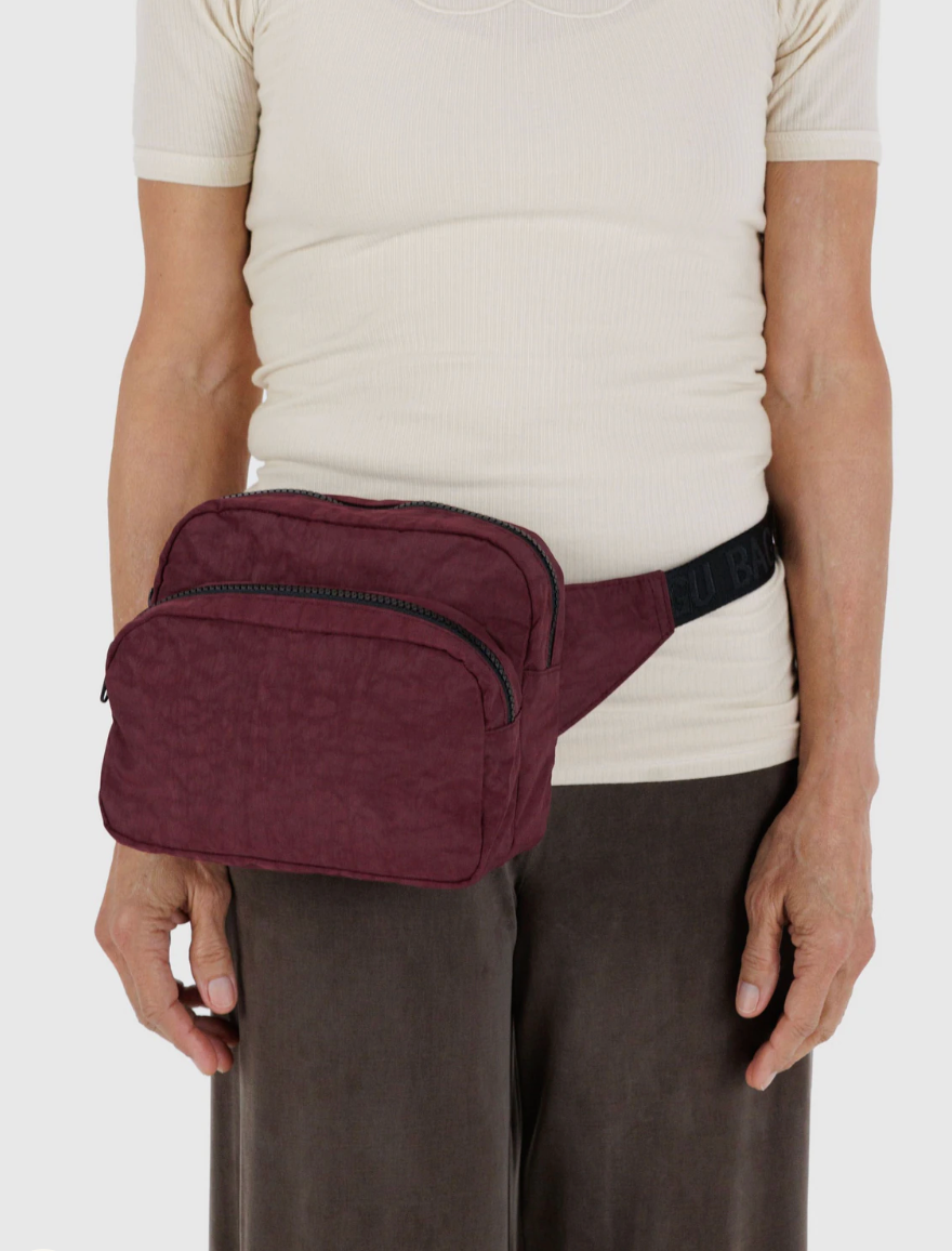 person wearring baggu mahogany waist bag with a black strap on a white background