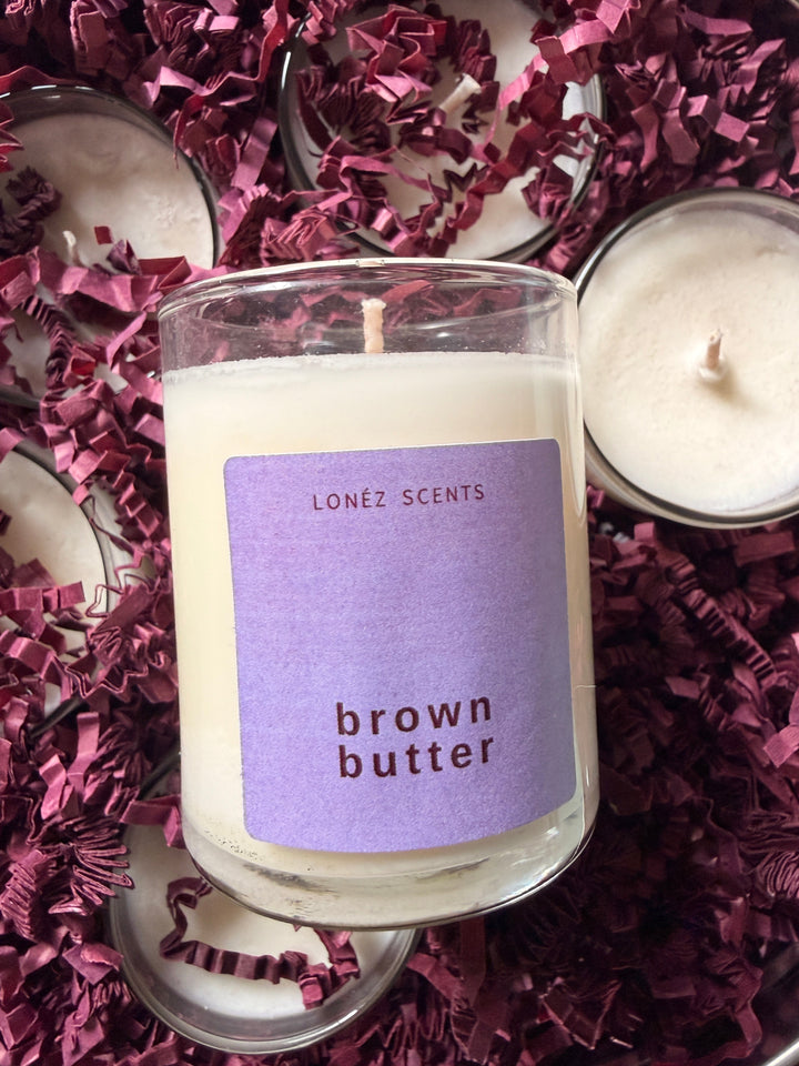 Candle labeled 'Brown Butter' by Lonez Scents on purple shredded paper