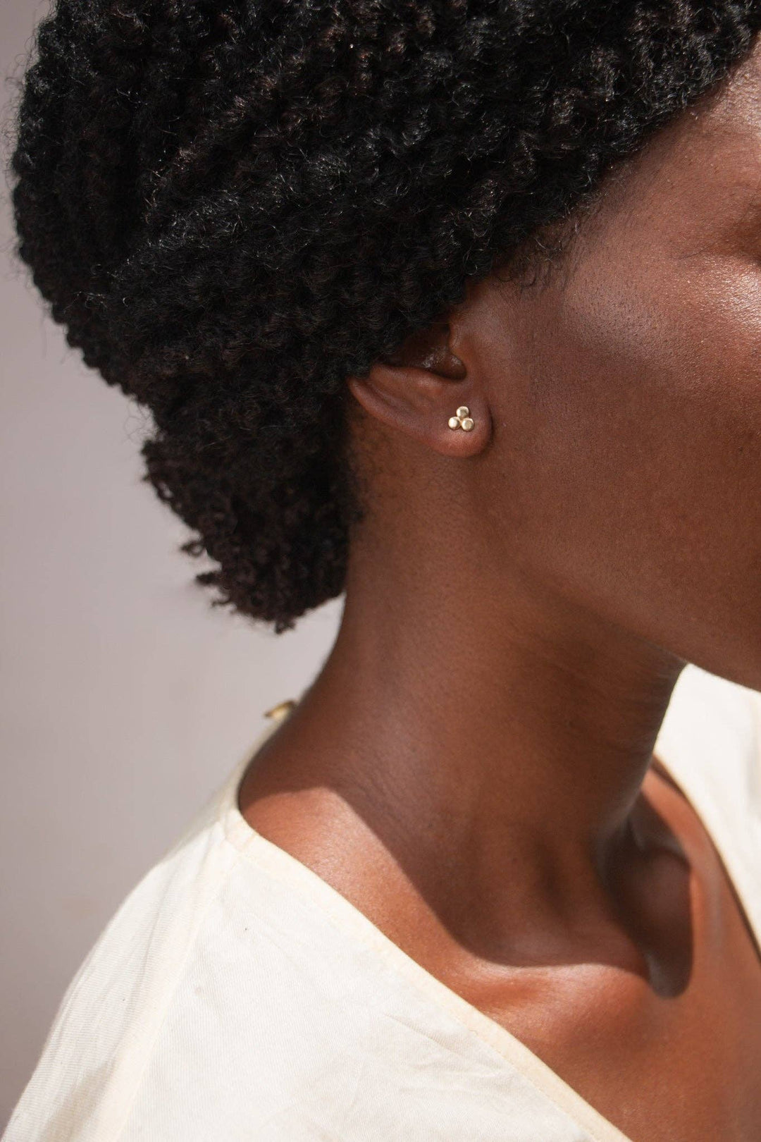 black women with twist updo style wearing light shirt, three dot earrings in pyramid shape