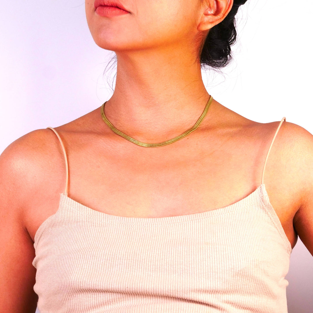 Woman wearing a brassnecklace with a plain background