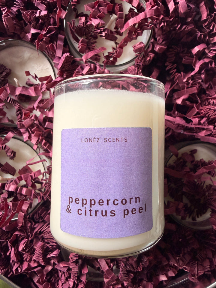 Candle with a purple label on a bed of purple shredded paper