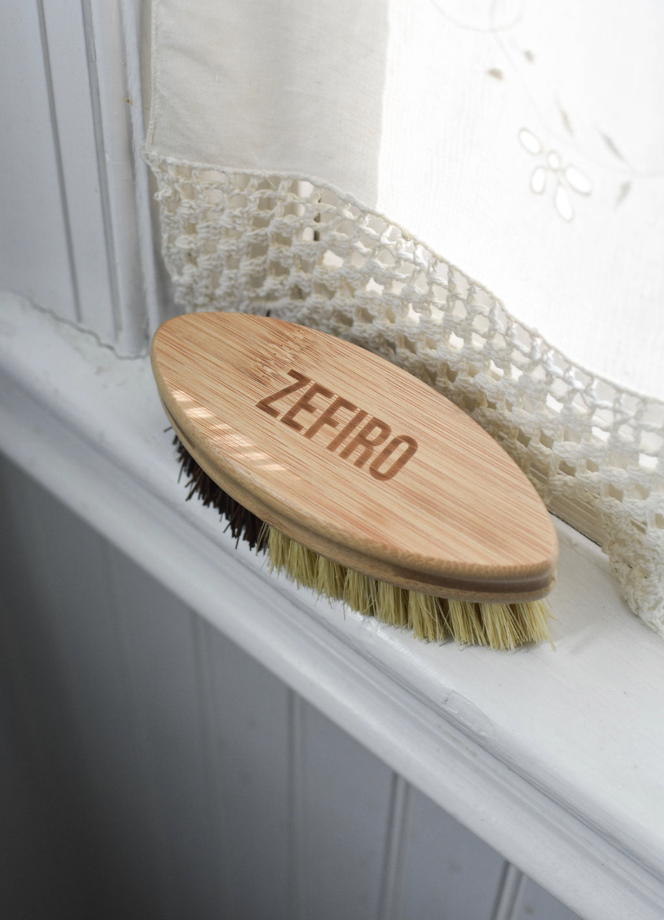 Wooden brush with bristles on a white surface, branded 'Zefiro'.