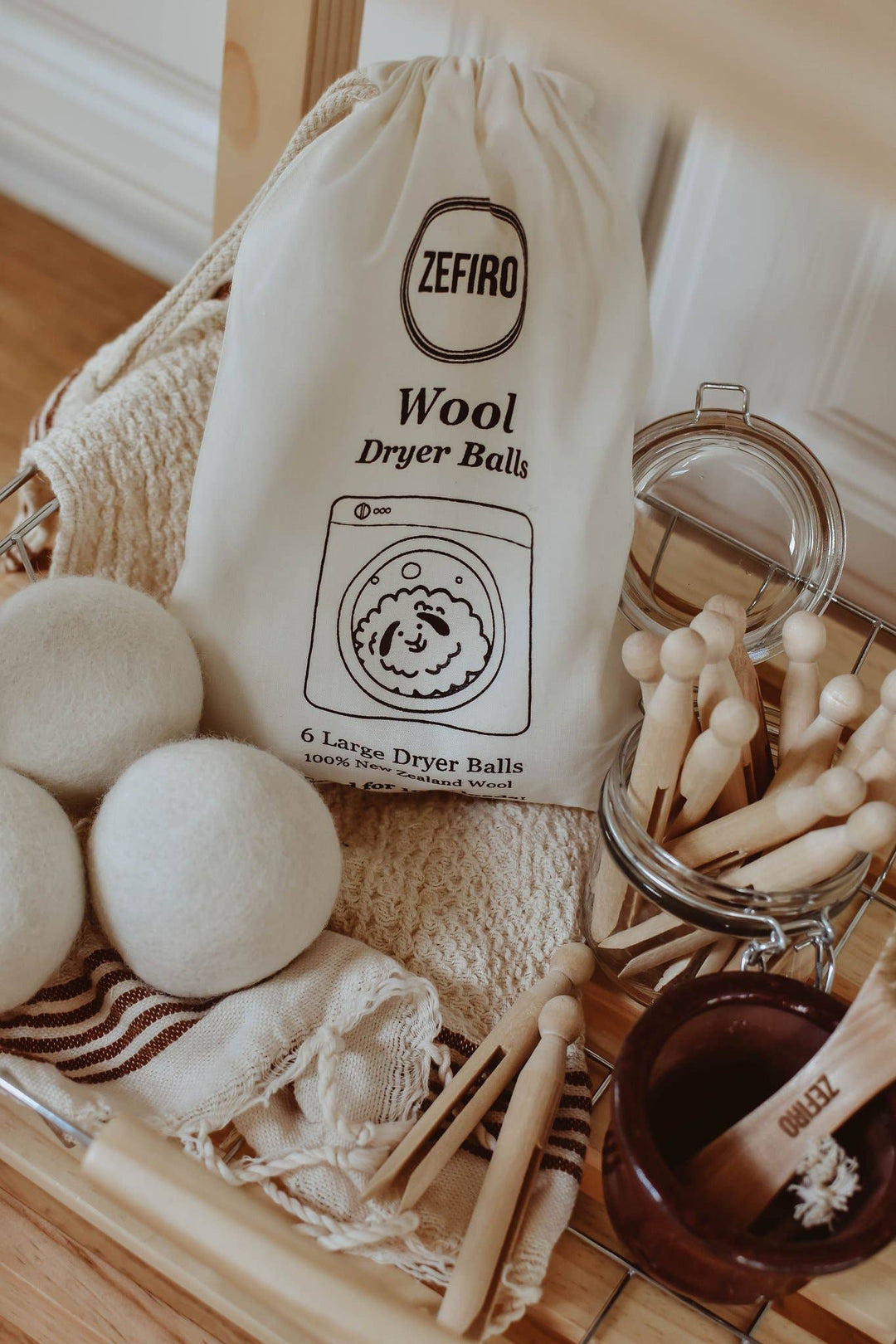 Zefiro wool dryer balls with a bag and cleaning tools on a wooden surface