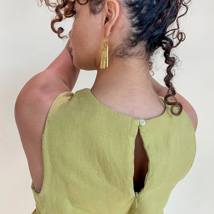 Woman seen from the back wearing gold earrings and a green dress
