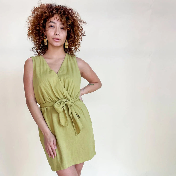Woman with curly hair wearing a green V neck dress